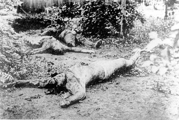  In the foreground, the corpse of the telegrapher Ponomarenko in the Cheka of Kharkov, Ukraine. His right hand was cut off and he shows deep cuts on his head. In the background are the bodies of two other victims of the Chekists.