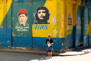 Woman walking by images of Ché Guevara and Hugo Chávez