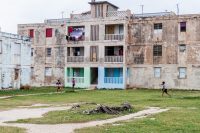 Children play baseball in front of derelict concrete blocks of flats in Gibara village, Cuba
